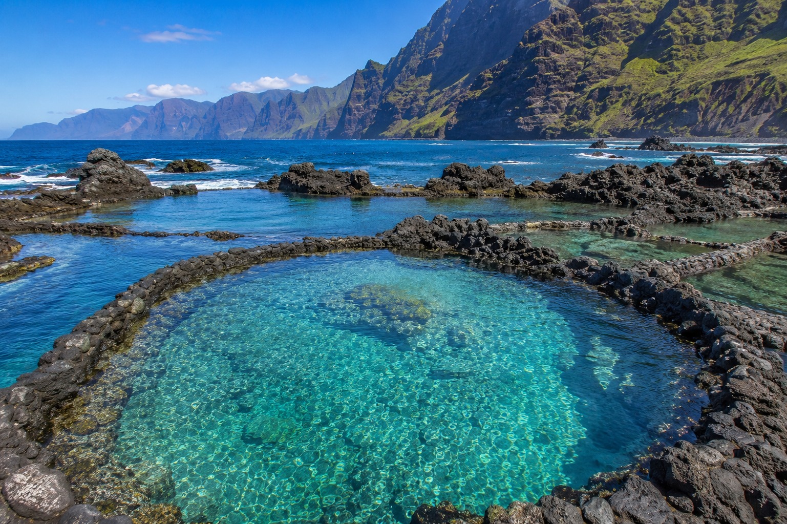 Las Salinas naturliga vulkanpooler i Agaete på norra Gran Canaria med kristallklart turkost vatten i svarta basaltbassänger och branta gröna klippor